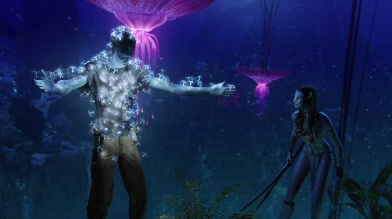 Settings Ideas and Examples for Film Scenes 10 A glowing blue figure stands with arms out as white spirit-like seeds float around him in a bioluminescent alien forest, watched by a Na’vi woman