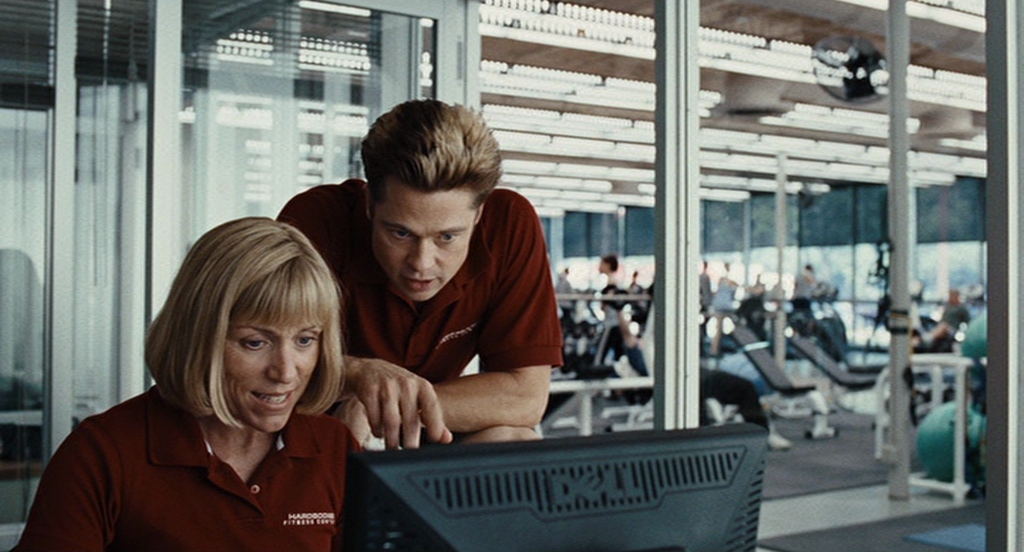 What Is a Color Scheme? Definition & Uses Explained 7 Two gym employees in red shirts look at a computer screen in a bright fitness center filled with teal and green exercise equipment.