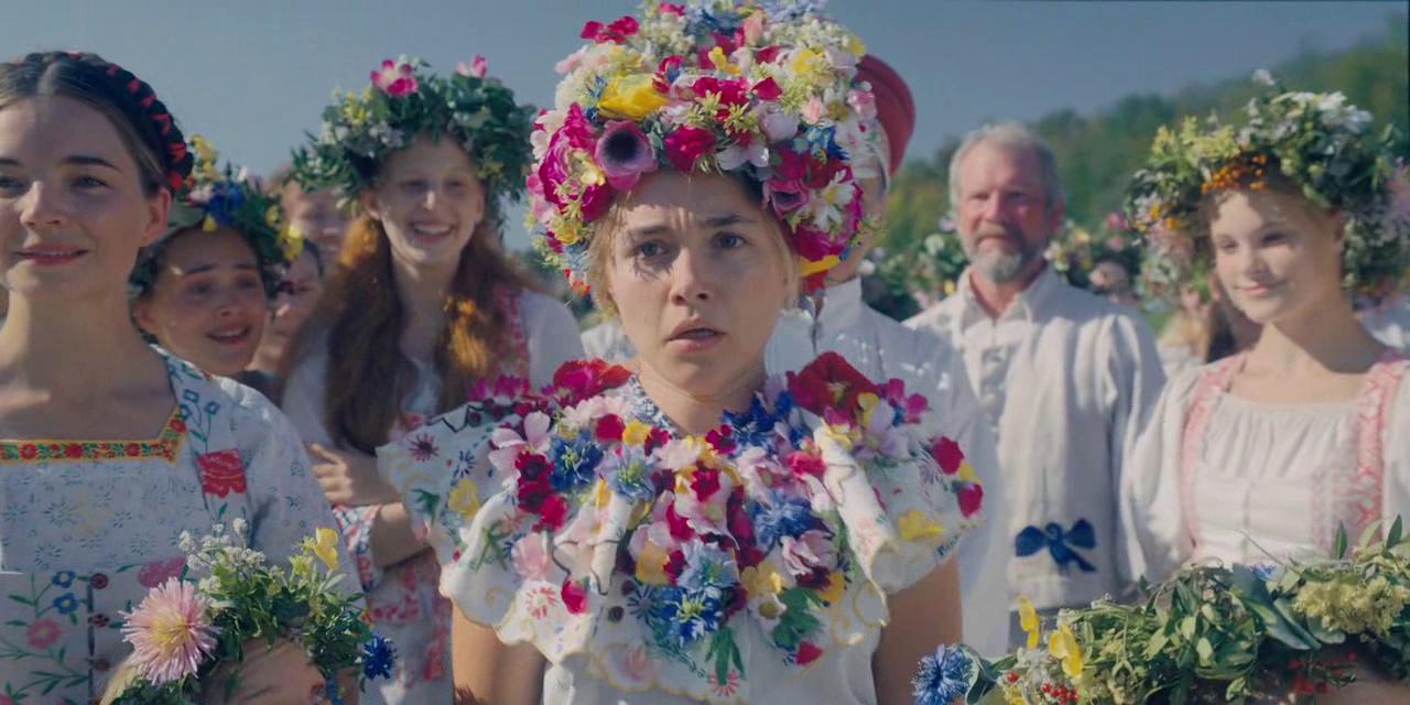 What Is a Color Palette? How to Use it in Film (+Free Planner) 12 Dani stands in a bright field wearing a dress and crown covered in colorful flowers, surrounded by villagers in white.