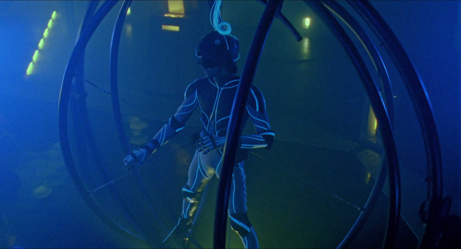 What Is Virtual Reality? Definition, Film Uses & Future Trends 2 A man in a glowing VR bodysuit suspended inside a metal simulator ring lit with blue lighting