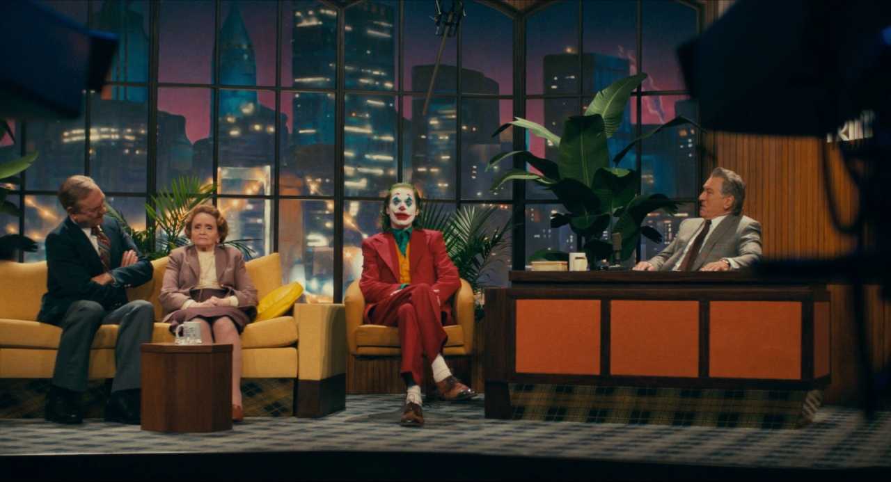 What Does a Colorist Do in Film? Role & Definition 5 Arthur Fleck in full Joker costume sitting between guests and host on a late-night talk show set with saturated colors and theatrical lighting