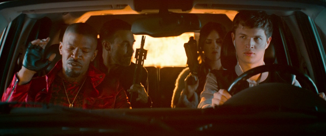 Settings Ideas and Examples for Film Scenes 14 Four people inside a car during a getaway, driver focused, others holding guns, with an explosion behind them