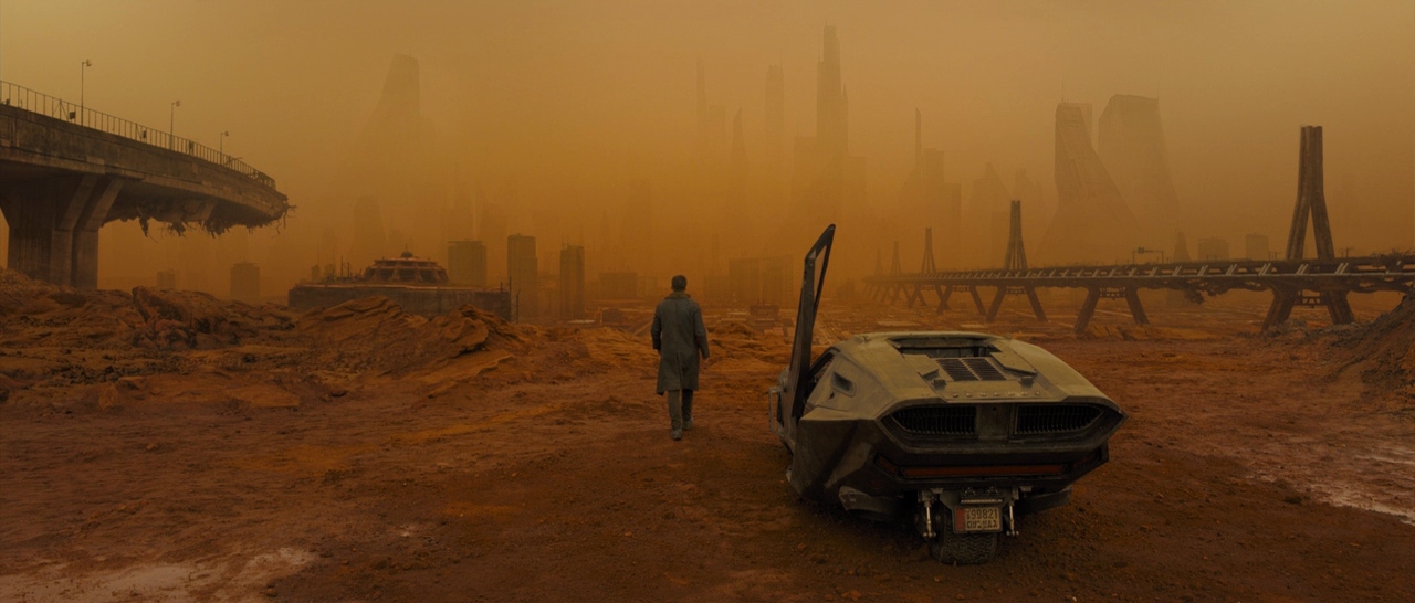 What Is an Analogous Color Scheme? Definition & Film Examples 4 A lone figure walks across a desolate, orange-tinted landscape with a futuristic car and ruined city in the background