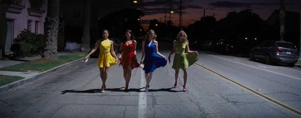 What Is a Color Palette? How to Use it in Film (+Free Planner) 6 Four women wearing bright red, yellow, blue, and green dresses walk down a street at dusk