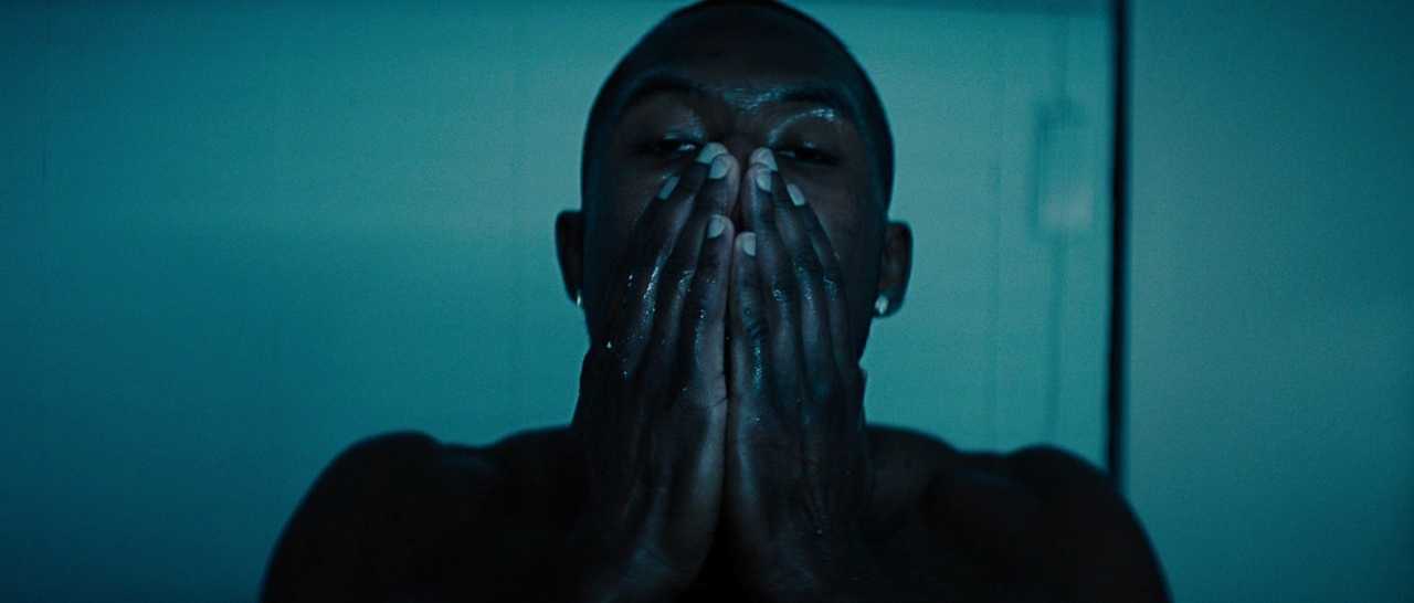 What Does a Colorist Do in Film? Role & Definition 4 Chiron in a dim cyan-lit bathroom, hands covering his face in silence and shadow