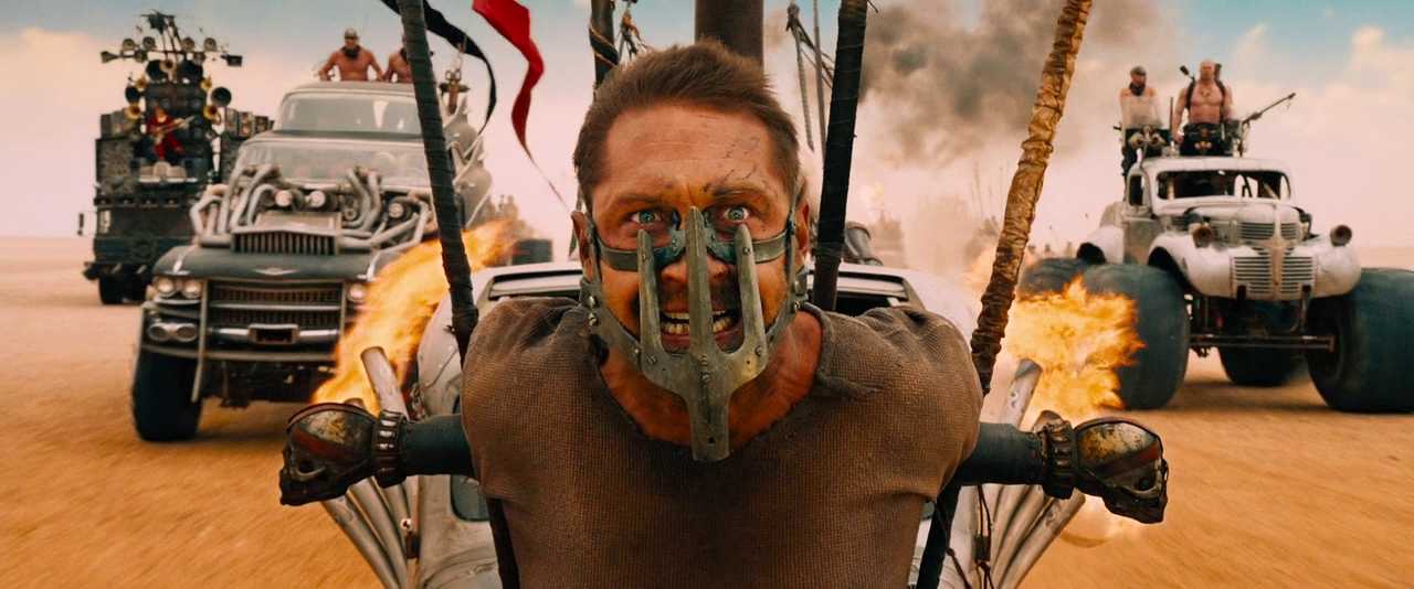 What Is Development Hell in Film? Meaning, Causes, Examples 2 Tom Hardy strapped to the front of a speeding vehicle in Mad Max: Fury Road (2015)