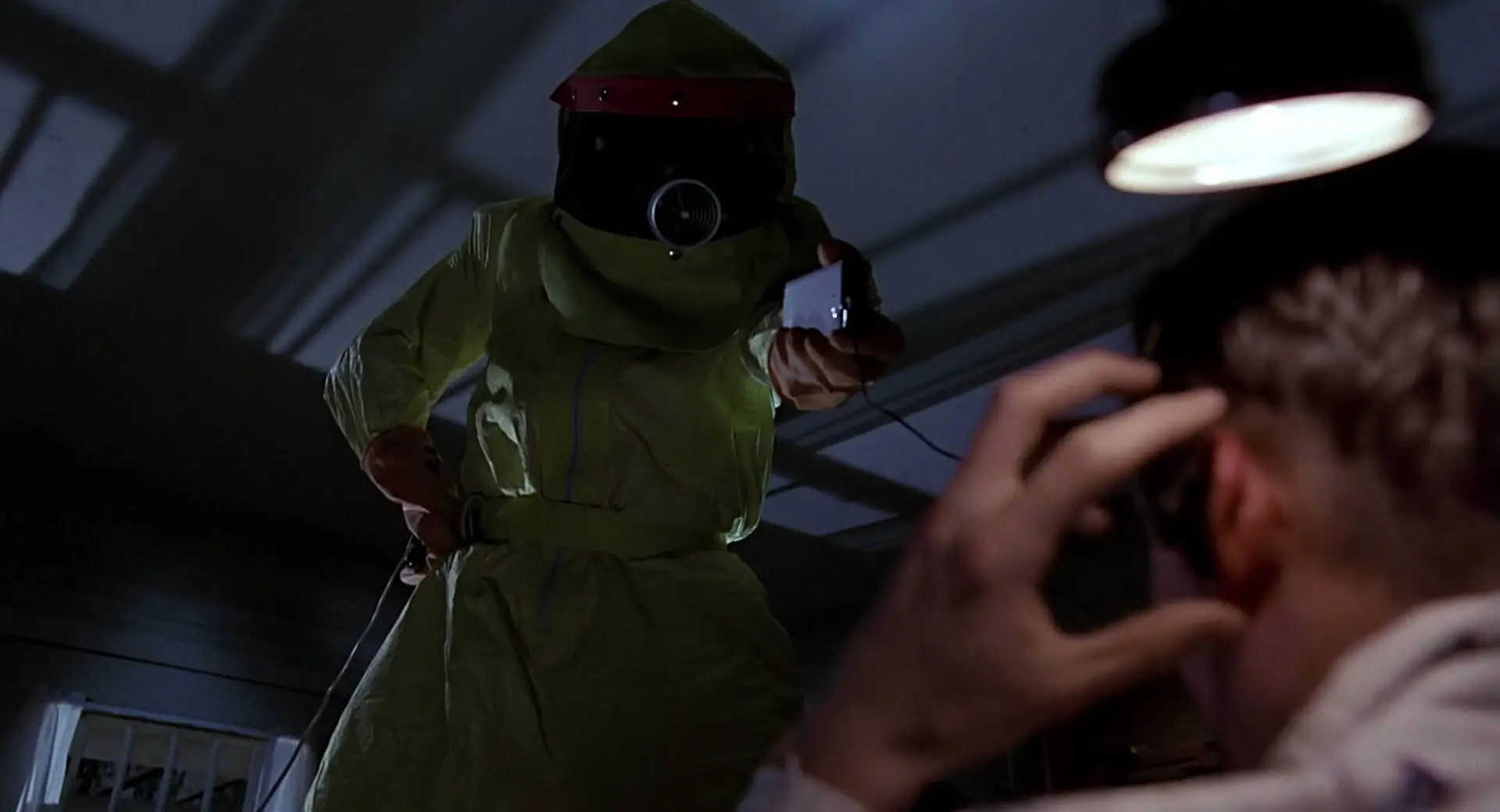What Is a Working Title in Film? Definition and Examples 7 A figure in a yellow hazmat suit looms over a frightened man, lit from above in a dark bedroom
