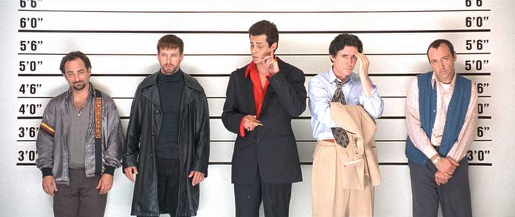 Best Mystery Movies of All Time: 25 Picks Explained 20 Five men stand in a police lineup in front of a height chart, facing the camera with different poses and expressions.