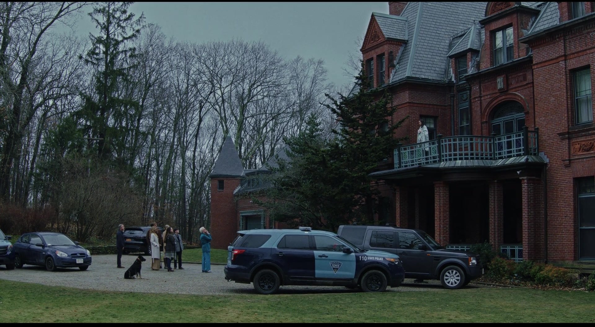 What is a Mystery Movie? Definition, Key Traits and Examples 3 Police cars and investigators stand outside a large mansion while family members watch from the ground and a balcony, establishing a crime scene under investigation.