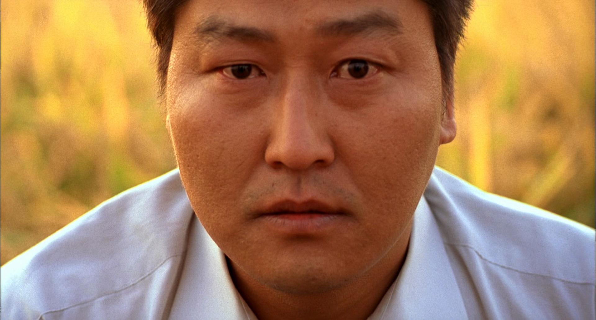 Best Mystery Movies of All Time: 25 Picks Explained 23 Close-up of a man outdoors staring straight ahead, with warm, blurred background colors behind him.