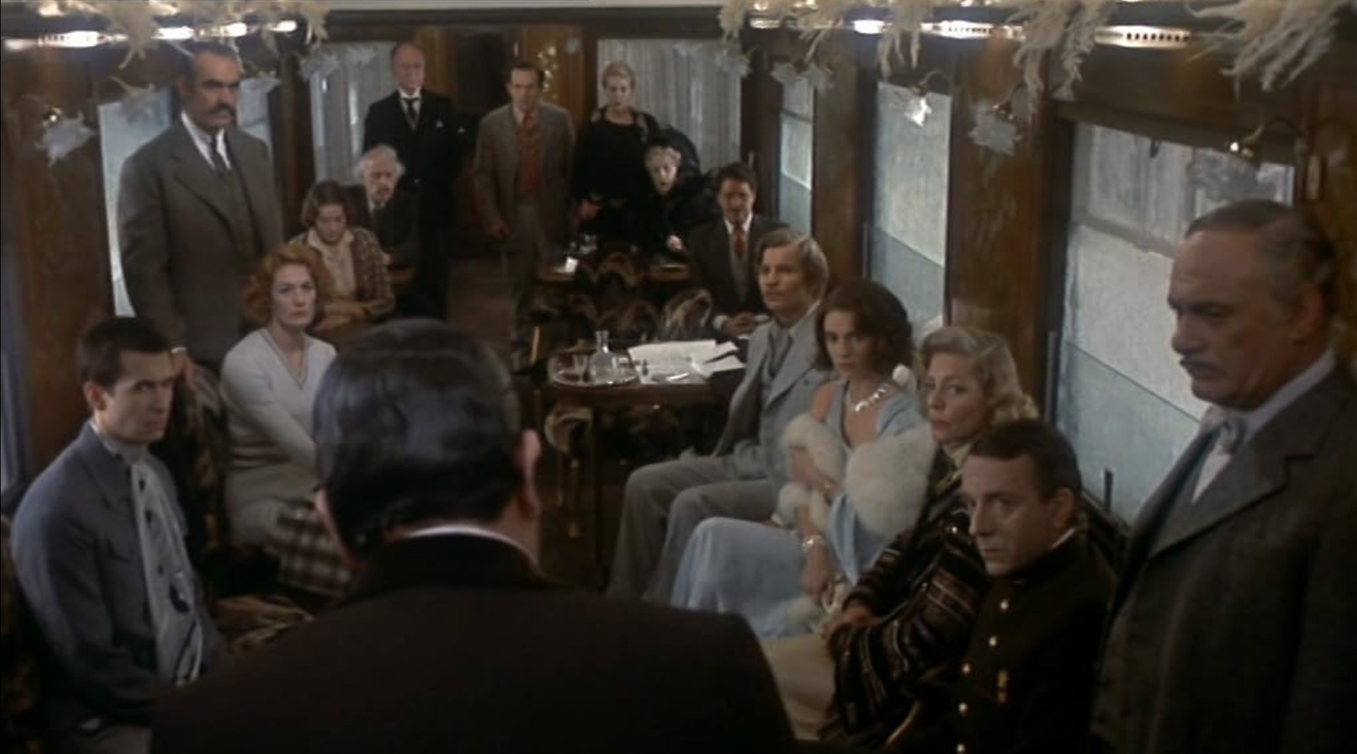 Best Mystery Movies of All Time: 25 Picks Explained 5 A crowded train dining car with many passengers seated and standing, all facing toward a man in the foreground as if listening to an announcement.