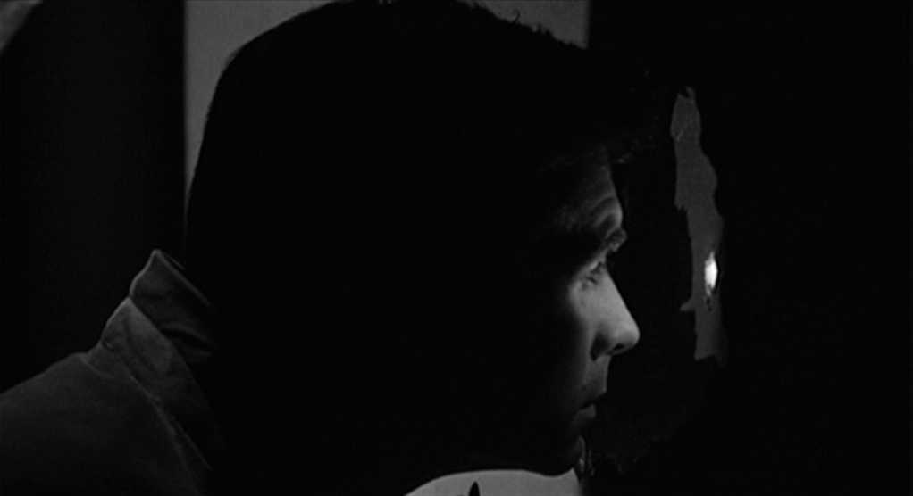 Psychoanalytic Film Theory: Definition and Key Concepts 3 Black-and-white close-up profile of Norman Bates peering into a small peephole, his eye lit while the rest of his face fades into shadow.