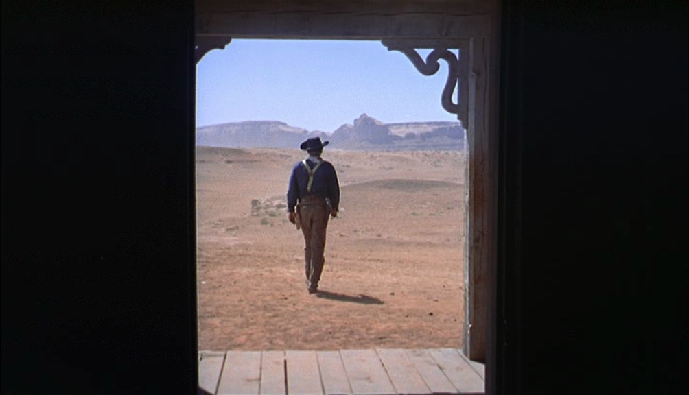 Structuralism in Film Theory: Key Concepts and Analysis 4 Seen from inside a dark house, a man in a hat walks away into a bright desert landscape, framed by the open doorway.