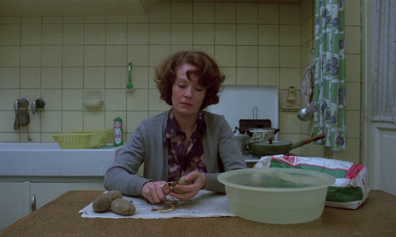 Spectatorship Theory: Film Studies Concepts and Analysis 5 A woman sits at a kitchen table peeling potatoes over newspaper. A large plastic bowl sits in the foreground, with a sink and stove behind her in a tiled kitchen.