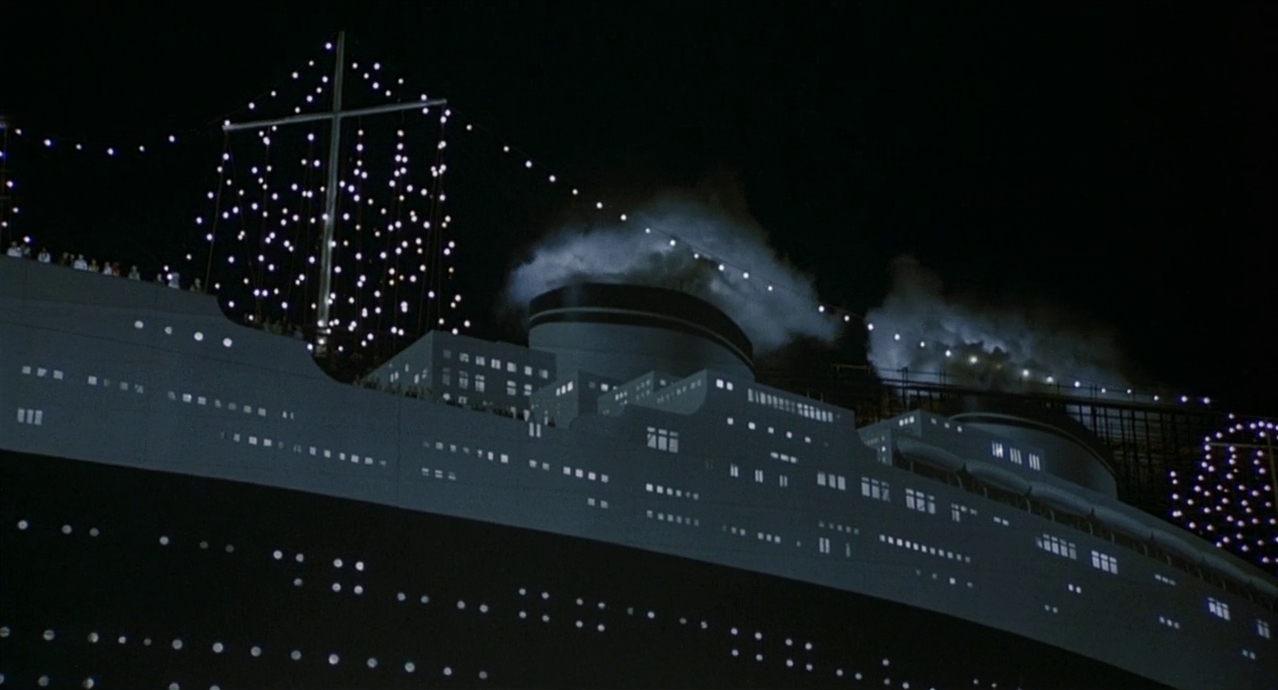 Fellini’s Dream Sequences: Craft Lessons from 8½ 3 Villagers in small boats gather on dark water as a massive illuminated ocean liner emerges through the fog at night.