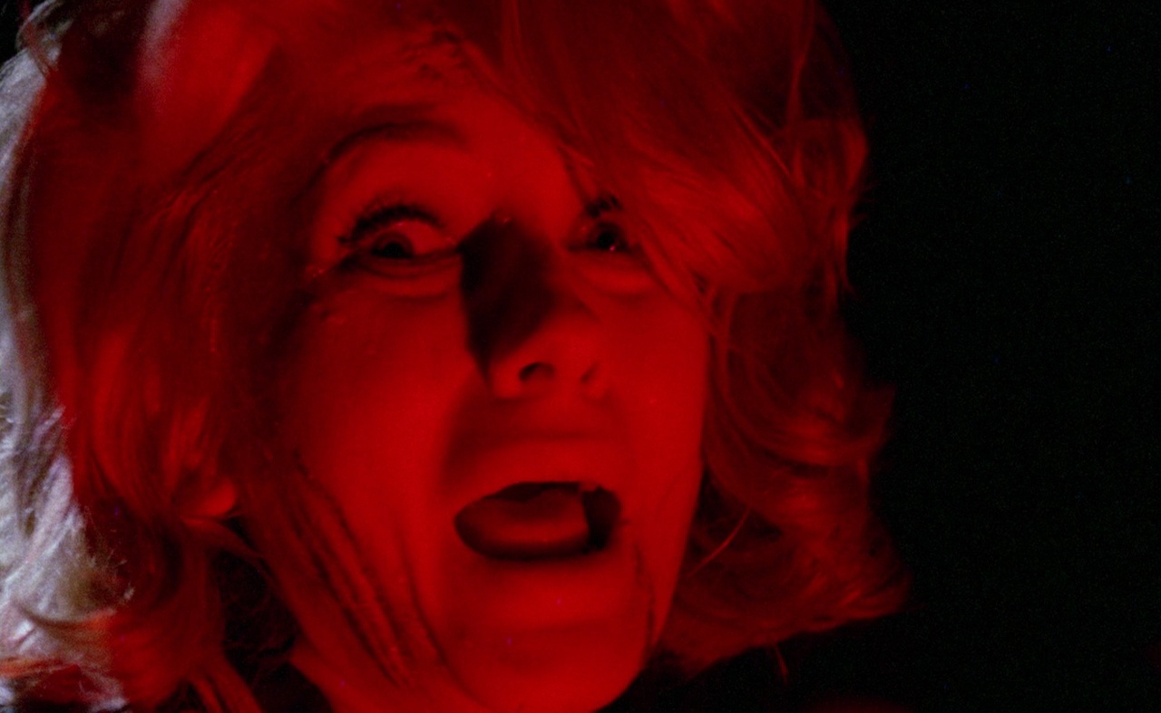 Mario Bava: The Man Who Invented Italian Horror 4 A frightened woman screams as intense red light covers her face and the surrounding room.